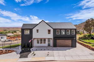 Modern farmhouse style home with a metal roof, concrete driveway, an attached garage, and a mountain view