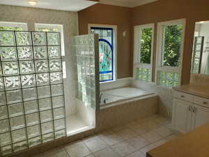 Full bath with light tile patterned floors, a bath, vanity, walk in shower, and crown molding