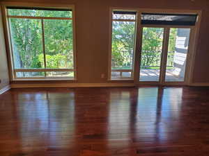 Spare room with baseboards and dark wood-type flooring