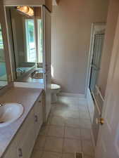 Bathroom with light tile patterned floors, vanity, and shower / bath combination with glass door