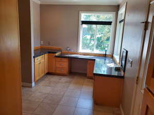 Kitchen with built in desk, crown molding, and light tile patterned flooring