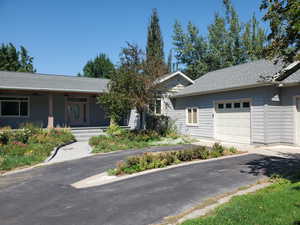 Ranch-style house featuring a shingled roof, an attached garage, a porch, and driveway