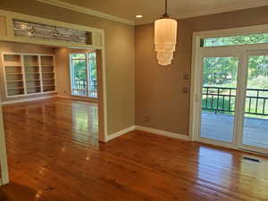 Unfurnished dining area featuring wood-type flooring, ornamental molding, built in shelves, and recessed lighting