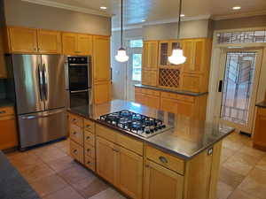 Kitchen with appliances with stainless steel finishes, crown molding, a kitchen island, light tile patterned floors, and recessed lighting