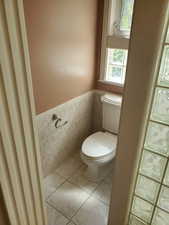 Bathroom featuring light tile patterned floors, tile walls, and wainscoting