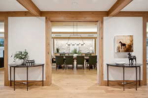 Dining space with beam ceiling, light wood finished floors, and a chandelier