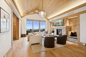 Living room with a fireplace, light wood finished floors, wood ceiling, and high vaulted ceiling