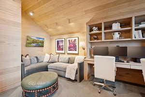 Carpeted office featuring lofted ceiling, wooden walls, wooden ceiling, and built in study area