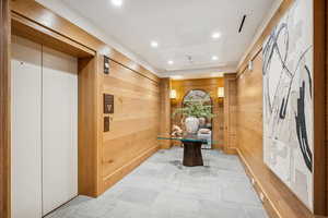 Hallway featuring elevator, recessed lighting, wood walls, and tile patterned floors