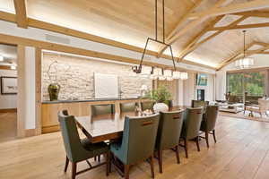 Dining area featuring light wood finished floors, a wood ceiling with exposed beams, and high vaulted ceiling