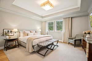 Bedroom featuring a tray ceiling, crown molding, and wood finished floors