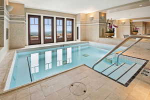 Indoor community pool featuring a hot tub