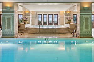 Indoor community pool featuring an in-ground hot tub