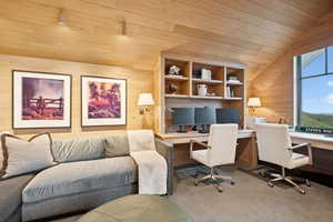 Home office featuring wooden walls, wood ceiling, carpet, lofted ceiling, and built in study area