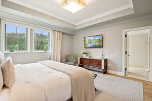 Bedroom featuring a tray ceiling, wood finished floors, and ornamental molding