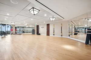 Exercise room with light wood-style flooring and recessed lighting