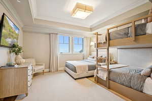 Carpeted bedroom featuring a tray ceiling and crown molding