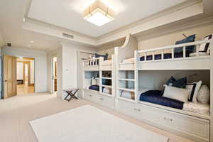 Bedroom with carpet floors, crown molding, and a raised ceiling