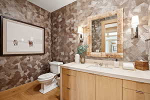 Half bath featuring vanity, wallpapered walls, and light wood-type flooring