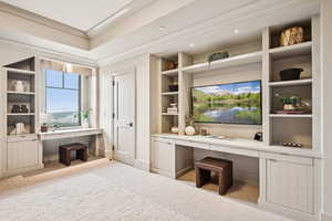 Mudroom featuring built in desk, carpet floors, built in shelves, and ornamental molding