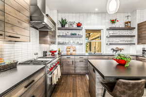 Kitchen with premium stove, tasteful backsplash, wall chimney range hood, a breakfast bar area, and a kitchen island