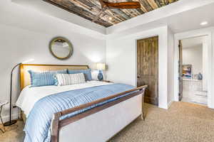 Carpeted bedroom with a tray ceiling, recessed lighting, and a ceiling fan