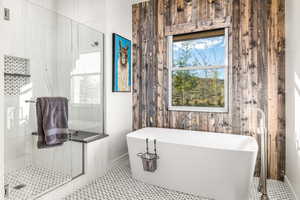 Full bath featuring a marble finish shower, a soaking tub, and healthy amount of natural light