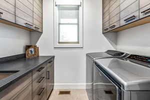 Laundry area with cabinet space, light tile patterned floors, and separate washer and dryer