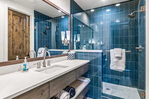 Full bath with a stall shower, vanity, and tile walls