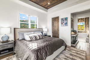Bedroom featuring dark wood-style flooring, wooden ceiling, recessed lighting, a raised ceiling, and multiple windows