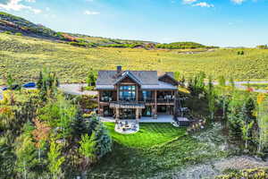 Rear view of property featuring an outdoor fire pit, a yard, a chimney, a balcony, and stairway