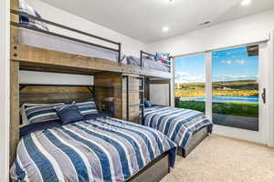 Carpeted bedroom with access to exterior, recessed lighting, and a water view