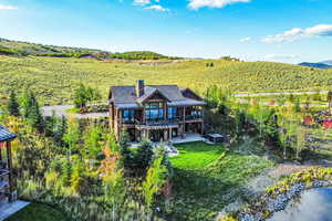 Back of house with a chimney, stairway, a metal roof, a water and mountain view, and a lawn