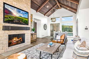 Living area with wood finished floors, high vaulted ceiling, a fireplace, and a wood ceiling with exposed beams