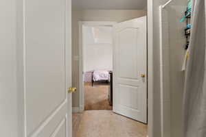 Bathroom with a tile shower, light tile patterned flooring, and connected bathroom