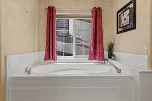 Full bath featuring a garden tub and a textured wall
