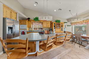 Kitchen featuring vaulted ceiling, white appliances, open shelves, a center island, and recessed lighting