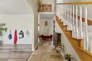 Foyer entrance featuring stone tile floors, arched walkways, and stairs