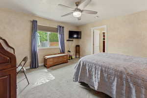 Bedroom featuring light carpet, a ceiling fan, a textured ceiling, and a textured wall
