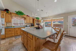 Kitchen with a kitchen bar, recessed lighting, a kitchen island, white appliances, and hanging light fixtures