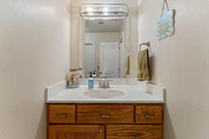 Bathroom with a textured wall and vanity