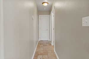 Hall featuring baseboards and stone tile flooring