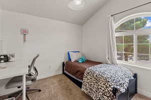 Bedroom with carpet flooring, lofted ceiling, and an office area