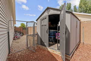 View of shed with a fenced backyard and a gate