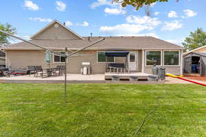 Back of house with roof with shingles, a lawn, a storage shed, and a wooden deck
