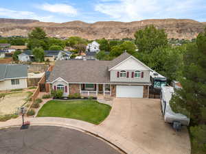 Traditional-style home with covered porch, a shingled roof, concrete driveway, a mountain view, and an attached garage