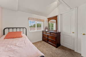 Bedroom featuring light carpet and lofted ceiling