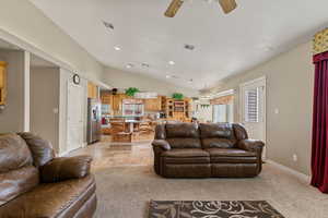 Living area featuring light carpet, recessed lighting, lofted ceiling, ceiling fan, and stone tile floors