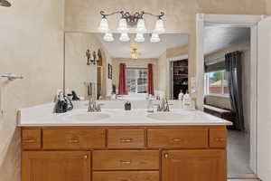Bathroom with healthy amount of natural light, double vanity, and a textured wall
