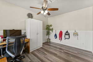 Office with a decorative wall, wood finished floors, a wainscoted wall, and ceiling fan
